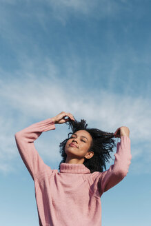 Portrait of young woman against sky touching her hair - LOTF00033