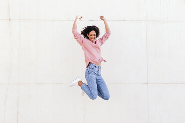 Happy young woman jumping in the air against light background - LOTF00036