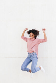 Glückliche junge Frau springt in die Luft vor hellem Hintergrund - LOTF00037