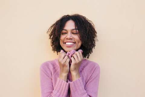 Porträt einer glücklichen jungen Frau mit rosa Pullover, lizenzfreies Stockfoto