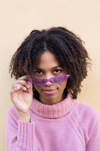 Porträt einer jungen Frau mit rosa Rollkragenpullover und lila Sonnenbrille, lizenzfreies Stockfoto