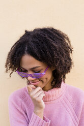 Porträt einer lächelnden jungen Frau mit rosa Pullover und lila Sonnenbrille - LOTF00044