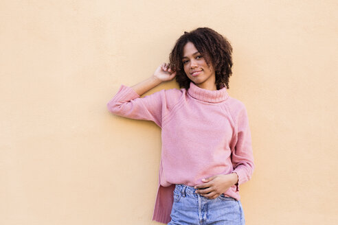 Portrait of smiling young woman wearing pink turtleneck pullover leaning against wall - LOTF00045