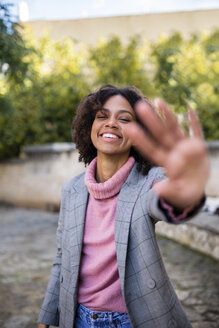 Portrait of laughing young woman raising hand - LOTF00048