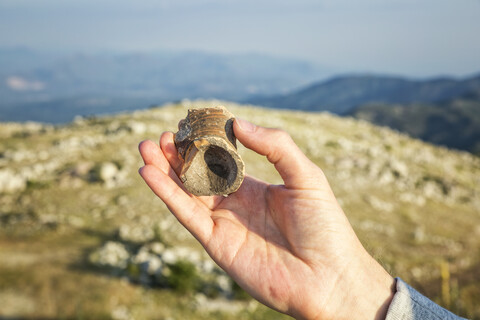 Griechenland, Peloponnes, Arkadien, Lykaion, Hand hält Fundstück einer Vase an der antiken Ausgrabungsstätte am Berg Profitis Ilias, lizenzfreies Stockfoto