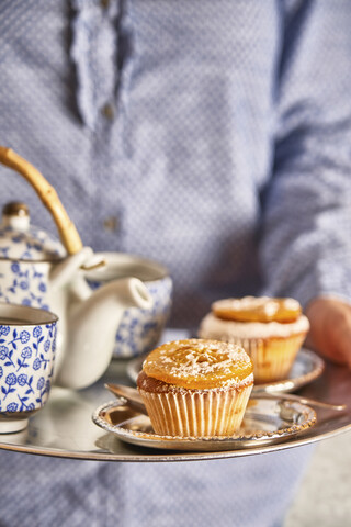 Frau serviert frische Muffins und Tee auf einem Silbertablett, Nahaufnahme, lizenzfreies Stockfoto