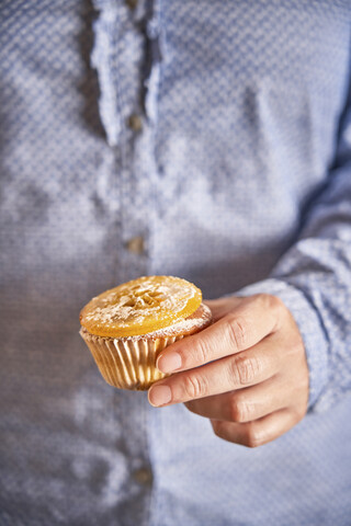 Frauenhand hält Muffin mit kandierter Orangenscheibe, Nahaufnahme, lizenzfreies Stockfoto