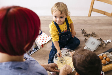 Lächelndes Kleinkind, das mit Mutter und Bruder am Küchentisch sitzt und Teig zubereitet - JRFF02335