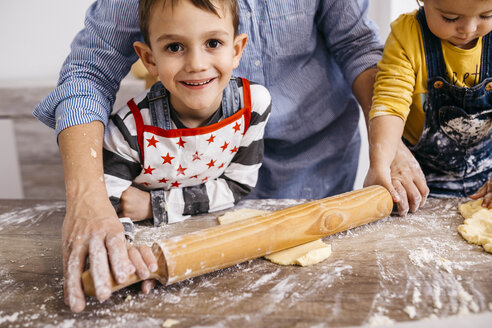 Porträt eines glücklichen Jungen, der zusammen mit seiner Mutter und seiner kleinen Schwester Kekse backt - JRFF02344