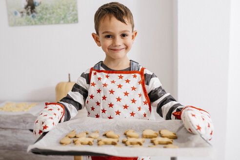 Porträt eines lächelnden kleinen Jungen, der ein Backblech mit selbstgebackenen Keksen hält - JRFF02357