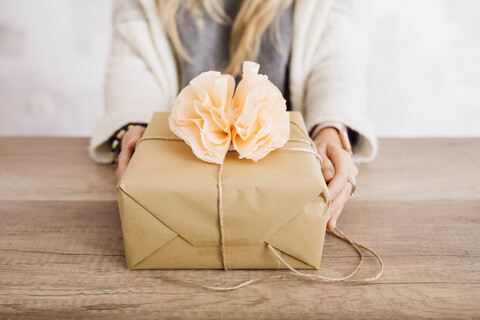 Junge Frau zeigt ein eingepacktes Geschenk in ihrem Atelier, lizenzfreies Stockfoto