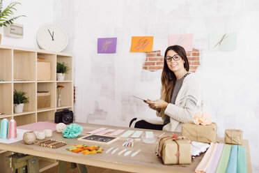 Young woman doing crafts at home, sitting at desk wth tablet - JRFF02389