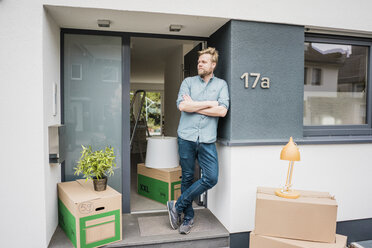 Man standing at house entrance surrounded by cardboard boxes - JOSF02684