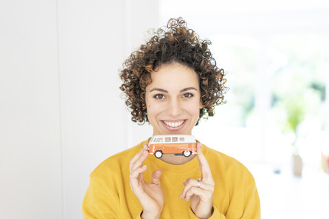 Porträt einer lächelnden Frau, die ein Modell eines Wohnmobils hält, lizenzfreies Stockfoto