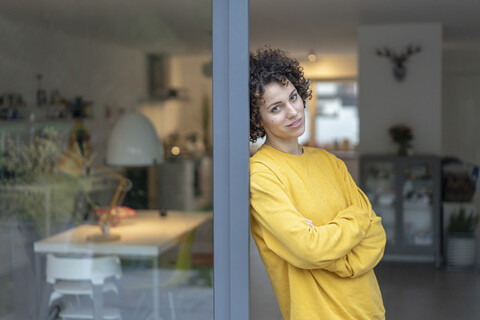 Portrait of woman leaning against terrace door at home stock photo