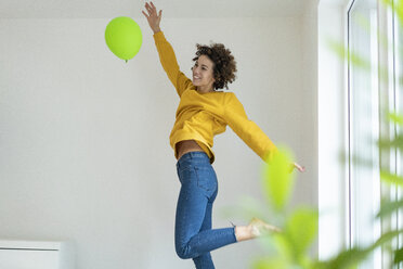 Glückliche Frau, die zu Hause mit einem Luftballon spielt - JOSF02716