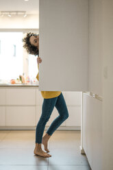 Porträt einer Frau am Kühlschrank in der Küche zu Hause - JOSF02718
