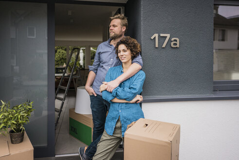 Couple standing at house entrance with cardboard boxes - JOSF02732