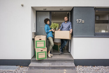 Couple standing at house entrance with cardboard boxes - JOSF02733