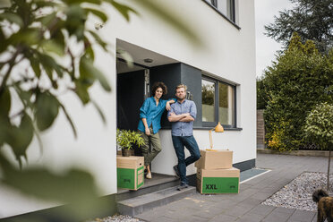 Couple standing at house entrance with cardboard boxes - JOSF02741