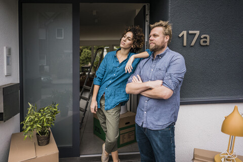 Couple standing at house entrance with cardboard boxes stock photo