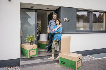 Couple standing at house entrance with cardboard boxes - JOSF02743