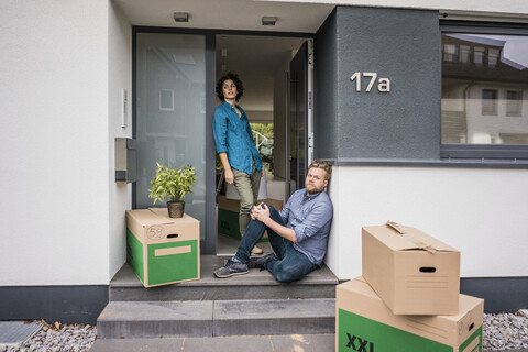 Couple at house entrance with cardboard boxes stock photo