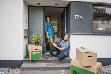 Couple at house entrance with cardboard boxes - JOSF02744