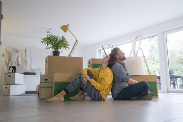 Couple sitting in living room with cardboard boxes - JOSF02760