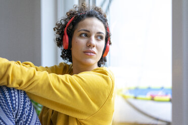Woman wearing headphones looking out of window - JOSF02763