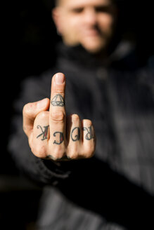 Tattooed man giving the finger, close-up - XCF00184