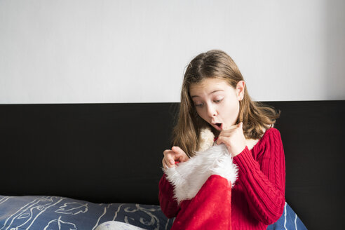Mädchen schaut in Weihnachtsmannmütze zu Hause - XCF00193