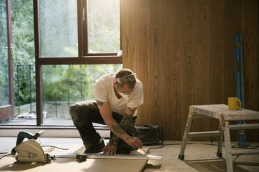 Construction worker measuring wood board in house - HOXF04234