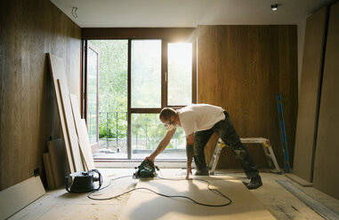 Construction worker using electric saw to cut wood in house - HOXF04236