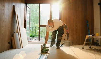 Construction worker using electric saw to cut wood in house - HOXF04244