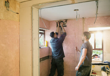 Bauarbeiter bei der Installation von Kupferrohren in einem Haus - HOXF04252