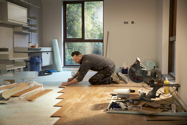 Construction worker laying hardwood flooring in house - HOXF04259