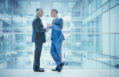 Geschäftsleute im Gespräch auf dem Balkon eines modernen Bürogebäudes, lizenzfreies Stockfoto