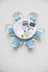 High angle view business laptop and paperwork on round table - HOXF04312