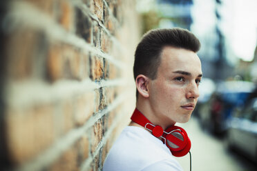 Serious teenage boy with headphones looking away - CAIF22409