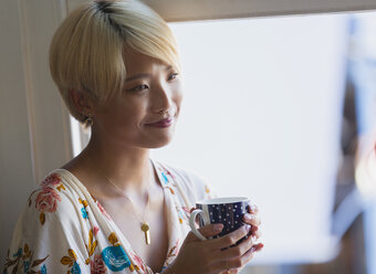 Smiling young woman drinking coffee - CAIF22494