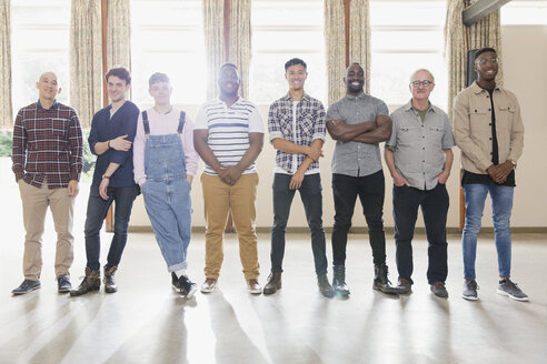 Portrait confident men standing in a row in community center - CAIF22502