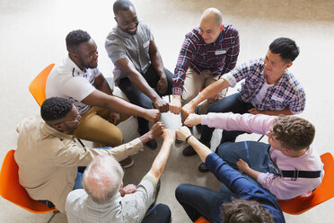 Men joining fists in circle in group therapy - CAIF22521