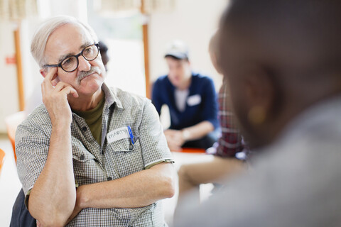 Aufmerksamer älterer Mann hört in der Gruppentherapie zu, lizenzfreies Stockfoto