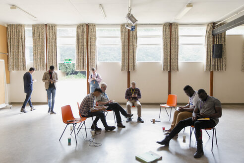 Men waiting, using smart phones in community center - CAIF22558