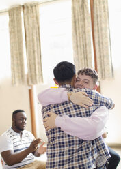 Men hugging in group therapy - CAIF22560