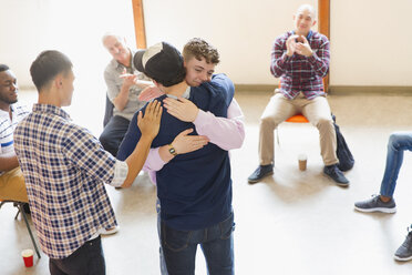 Men hugging and clapping in group therapy - CAIF22564