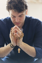 Gelassener Mann beim Beten mit Rosenkranz - CAIF22566