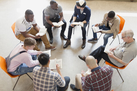 Männer lesen und diskutieren im Gebetskreis über die Bibel, lizenzfreies Stockfoto