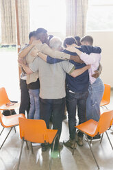 Men hugging in huddle in group therapy - CAIF22598